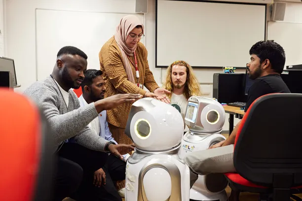 A group of student gathered around robotics equipment.
