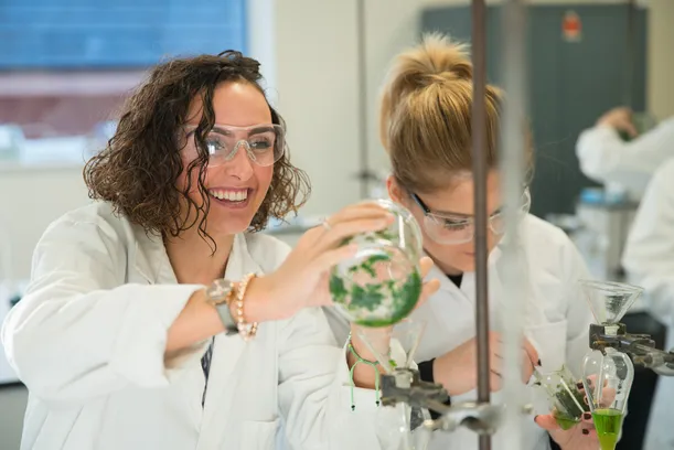 two female students enjoying working with chemistry lab equipment