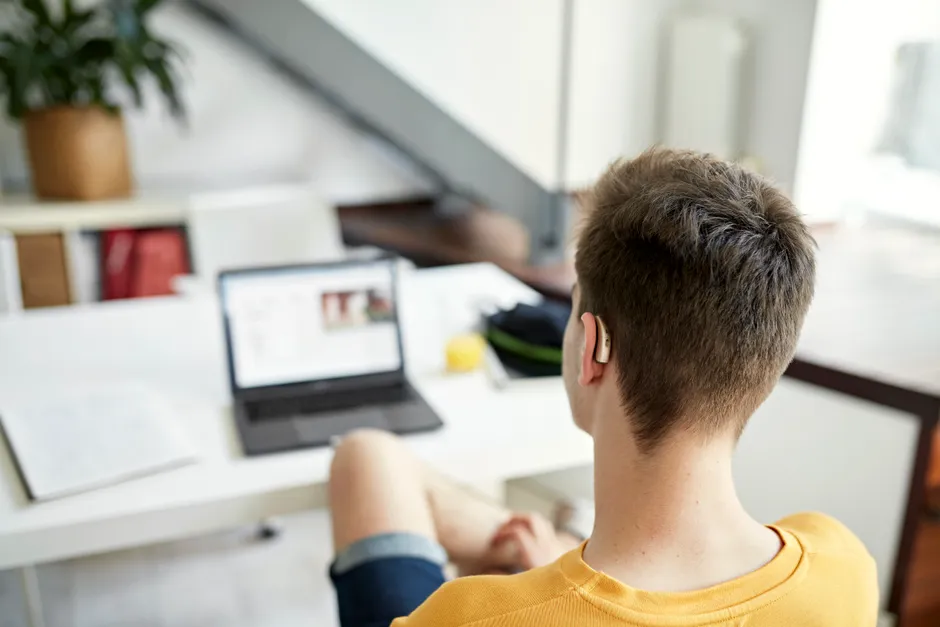 A deaf student sitting at a laptop studying