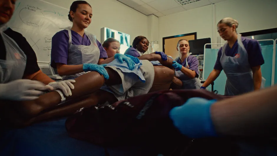A group of nursing students caring for a simulated patient in a hospital setting