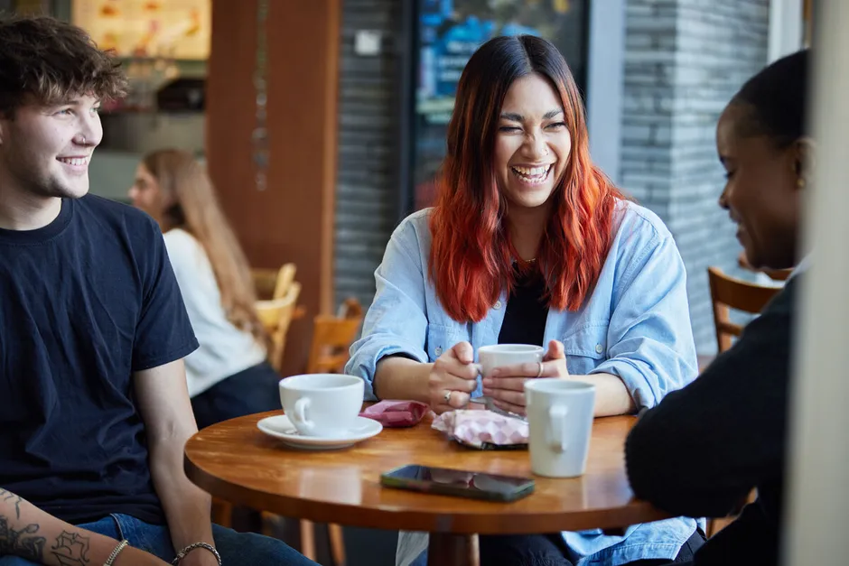 A group of student sat laughing and talking in Treforest Student's Union with a coffee