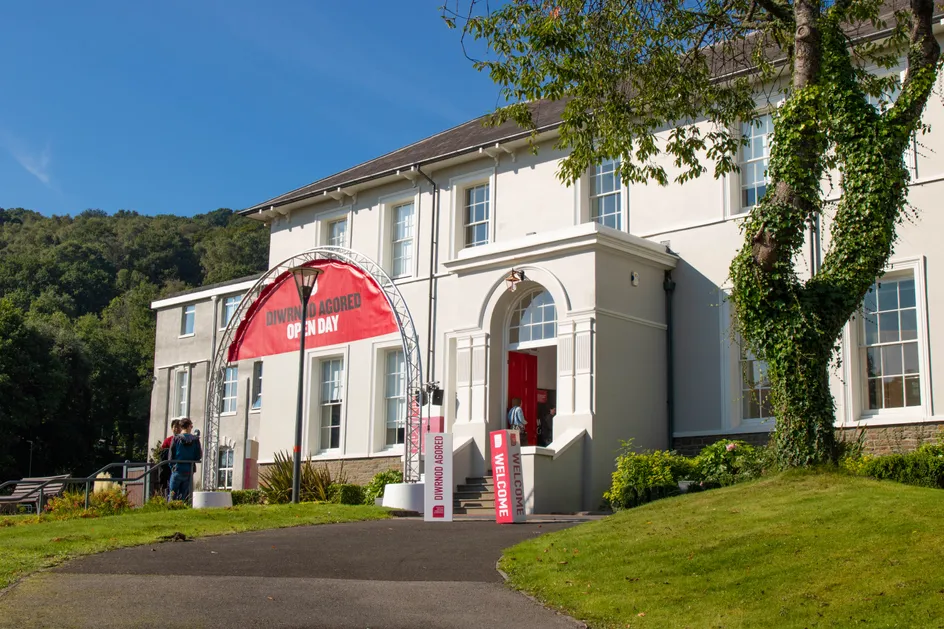 A large red open day banner outside Ty Crawshays on a sunny day.