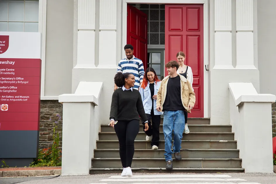 Students walking down a set of stairs from a campus building talking to each other.