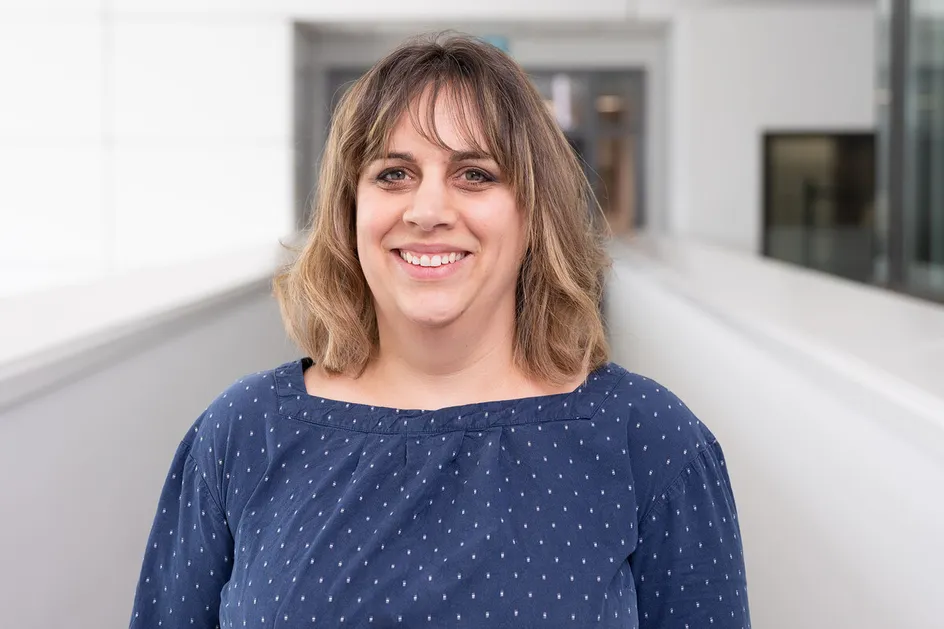 Professor Emily Underwood Lee smiles at the camera from a white balcony inside Cardiff Campus