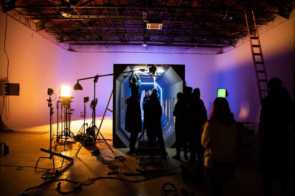 A group of students film inside a USW studio at Cardiff Creative Campus with ambient lighting