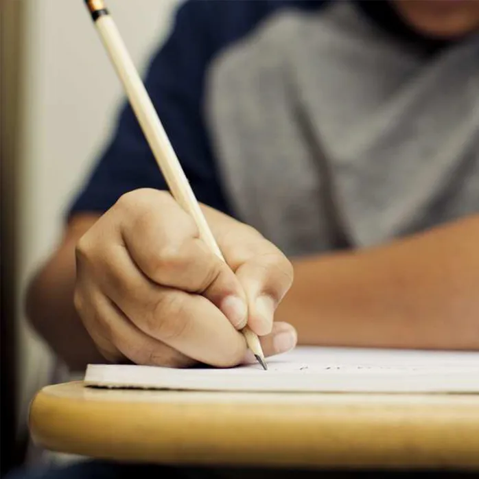 A student writing with a pencil and paper