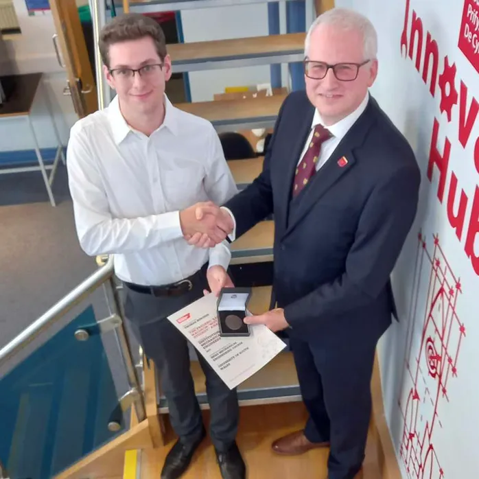 Myfyriwr graddedig, Tom Burgess, yn cael ei gyflwyno gyda Gwobr Myfyriwr Gorau Frederic Barnes Waldron Sefydliad y Peirianwyr Mecanyddol gan Dr Paul Davies