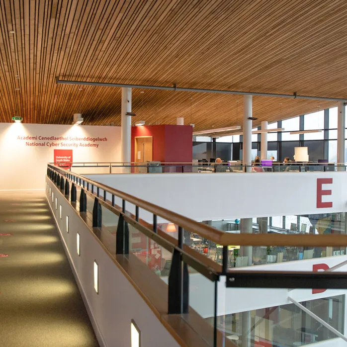 Llun mewnol o gampws Casnewydd gyda'r Academi Seiberddiogelwch Genedlaethol yn y pellter