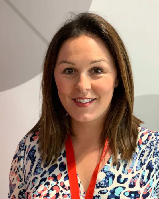 Katrina Cookson smiles at the camera. She is brunette and wears a patterned top.