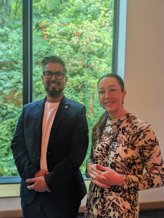 Two people are stood up and smiling at the camera. Sal Naseem, Inclusive culture expert, is with Hannah Coombs, USW’s Associate Dean of Partnerships and Development.