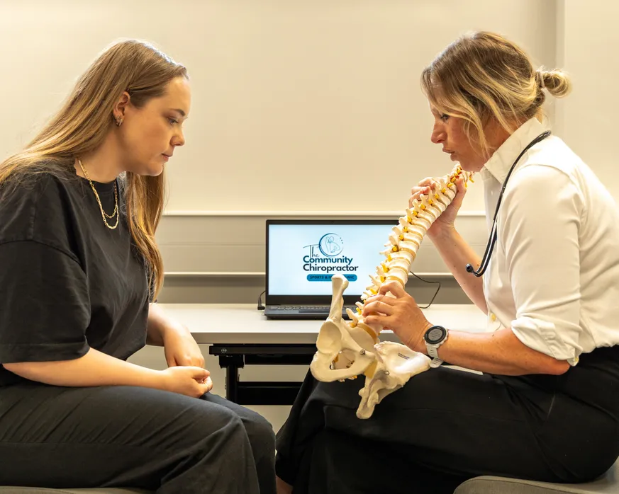 two females sitting, one holding and showing human bones