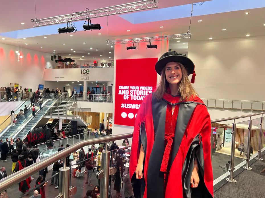 Mae Olivia Breen yn gwenu wrth y camera mewn cap graddio a gwn