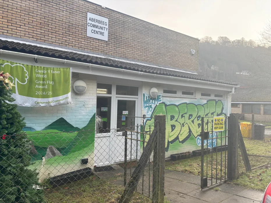A graffiti mural on a brick wall displaying the words 'Aberbeeg Community Centre' in bold, green and blue letters.