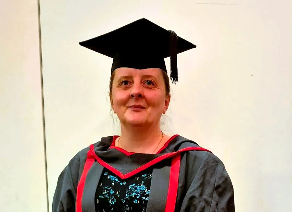 Beverley wearing red and black graduation gown and cap