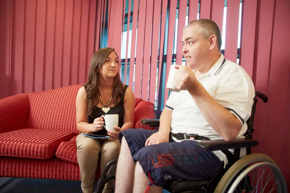A learning disability nursing student has a cup of tea with a client.