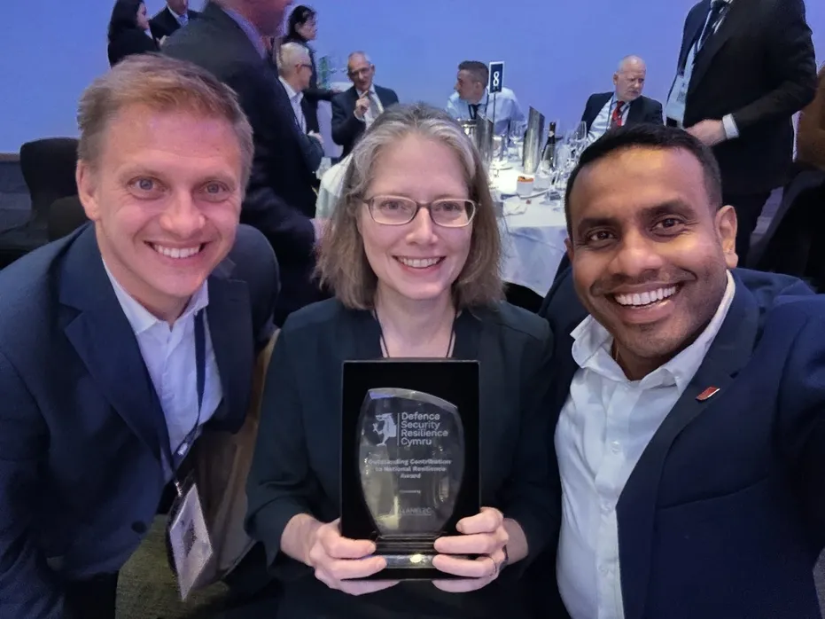Rhys Driscoll, Jill Stewart and Leshan Uggalla sat at the award event posing with a glass trophy.