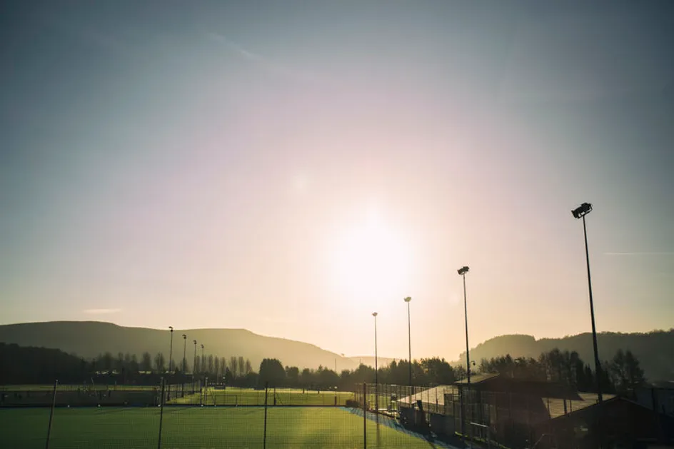 An outside shot of sport fields on a sunny day. There are mountains in the background.