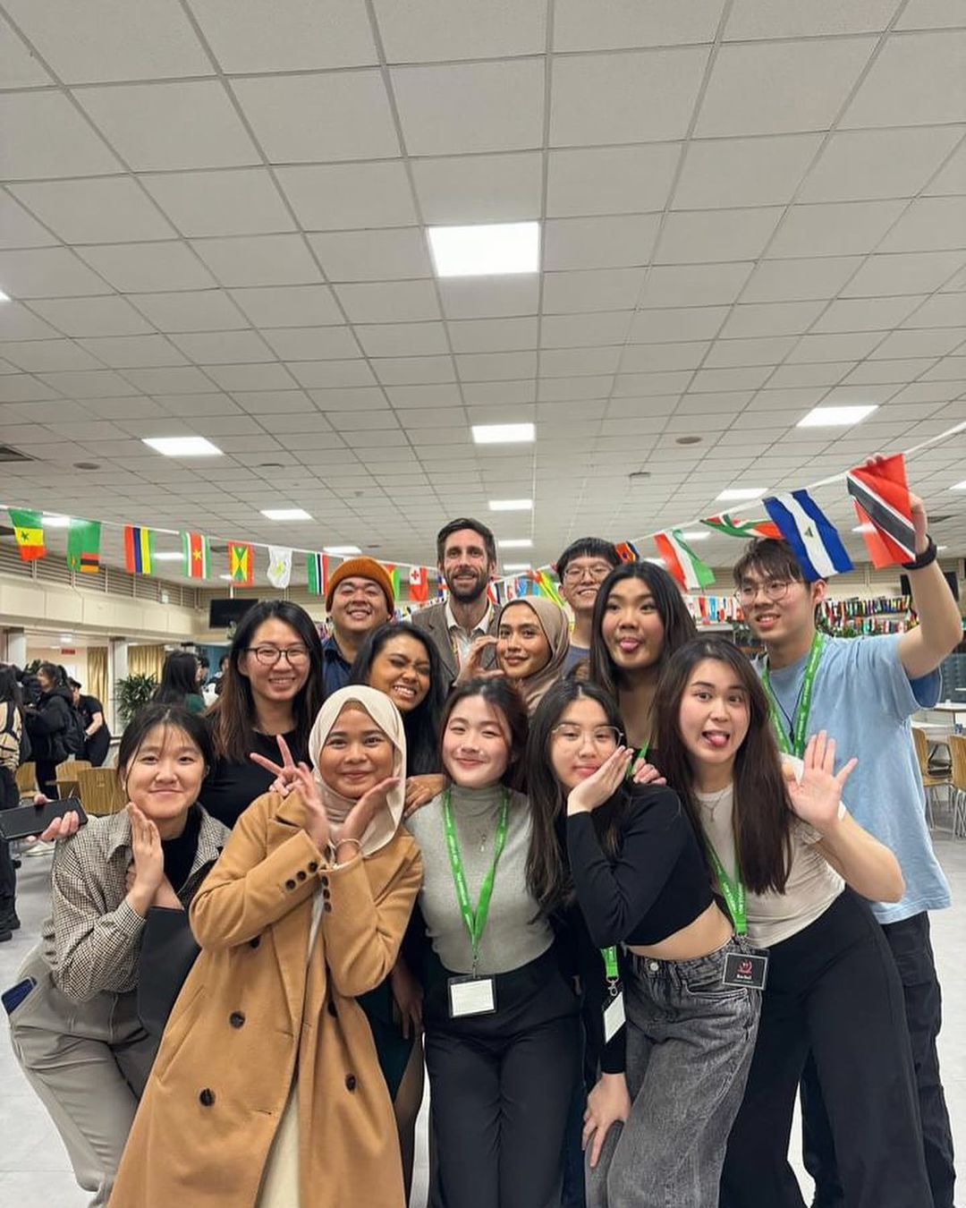 The USW Malaysian society smiling at the camera surrounded by flags of the world