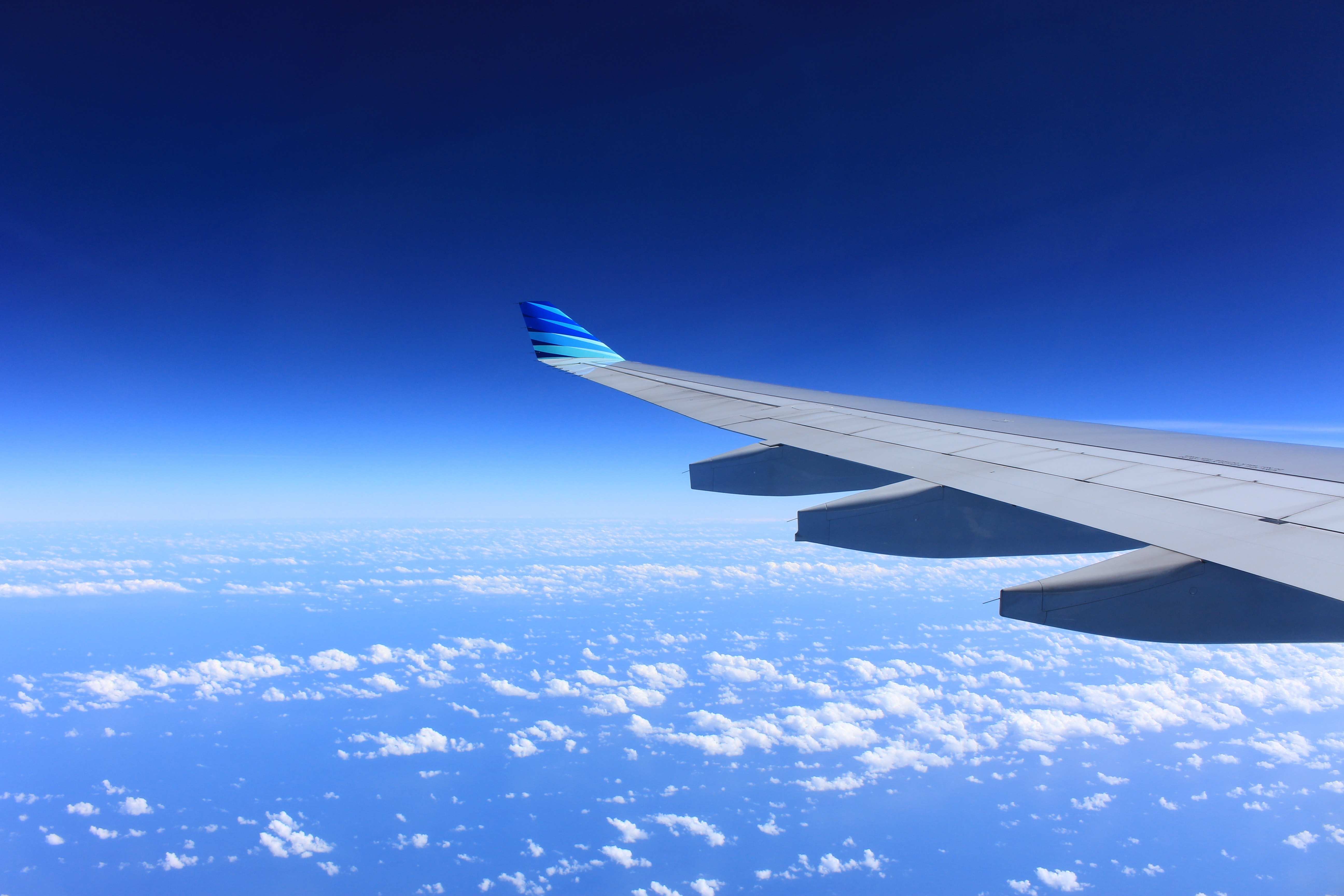wing of an airplane flying above the clouds with blue sky