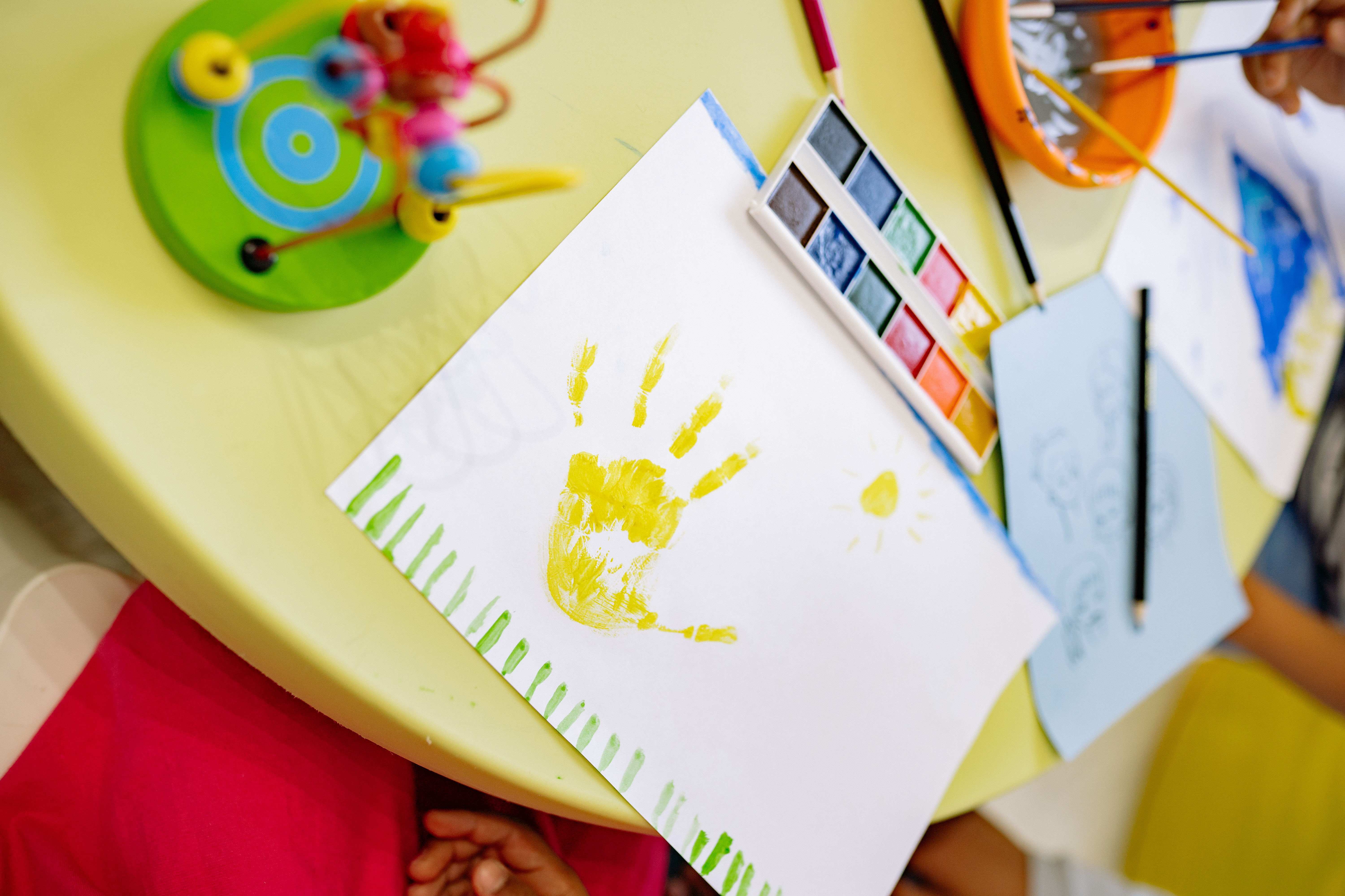 arts and craft table within a childcare facility with a handprint painting by a child on the table