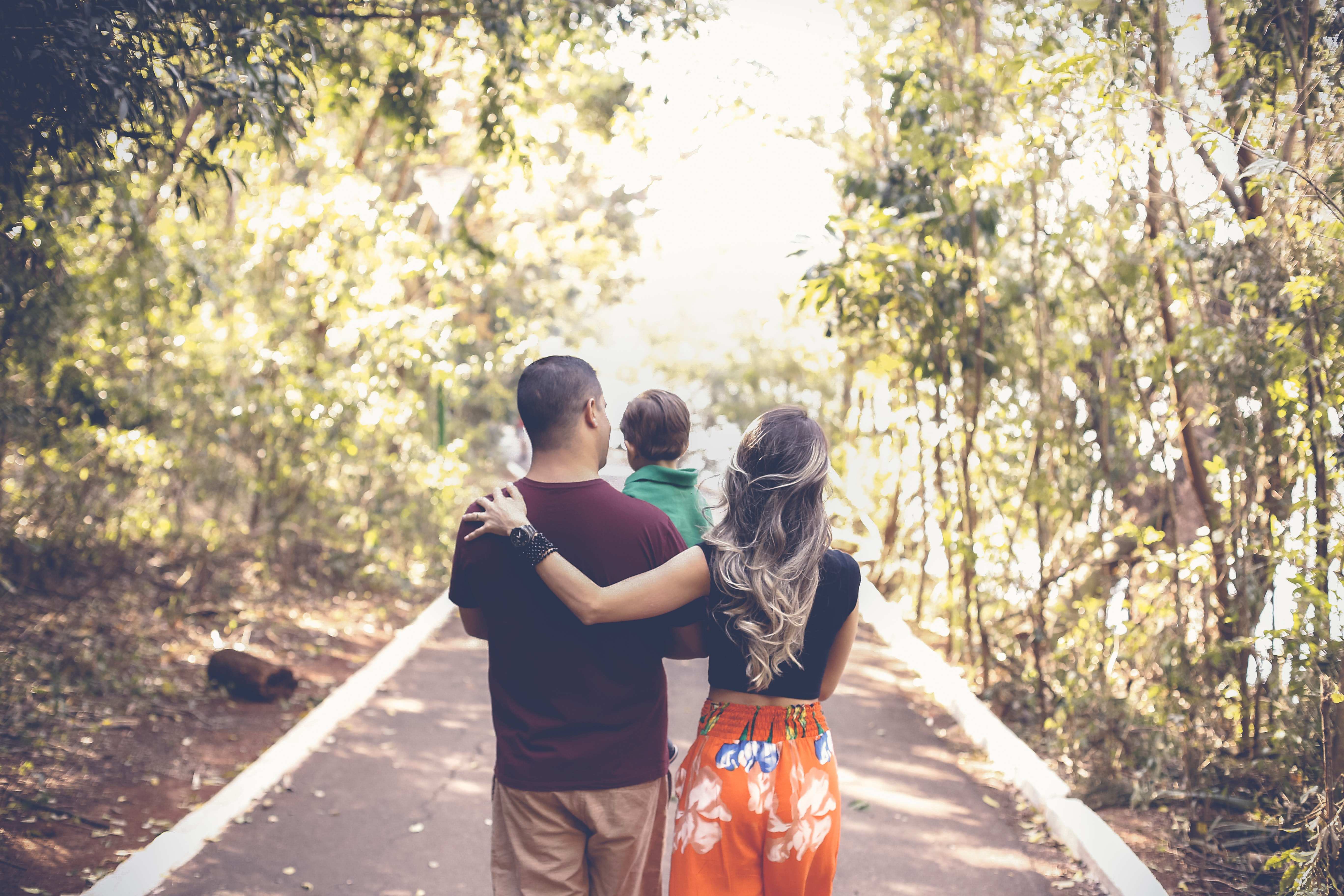two people walking with their child through a wooded area
