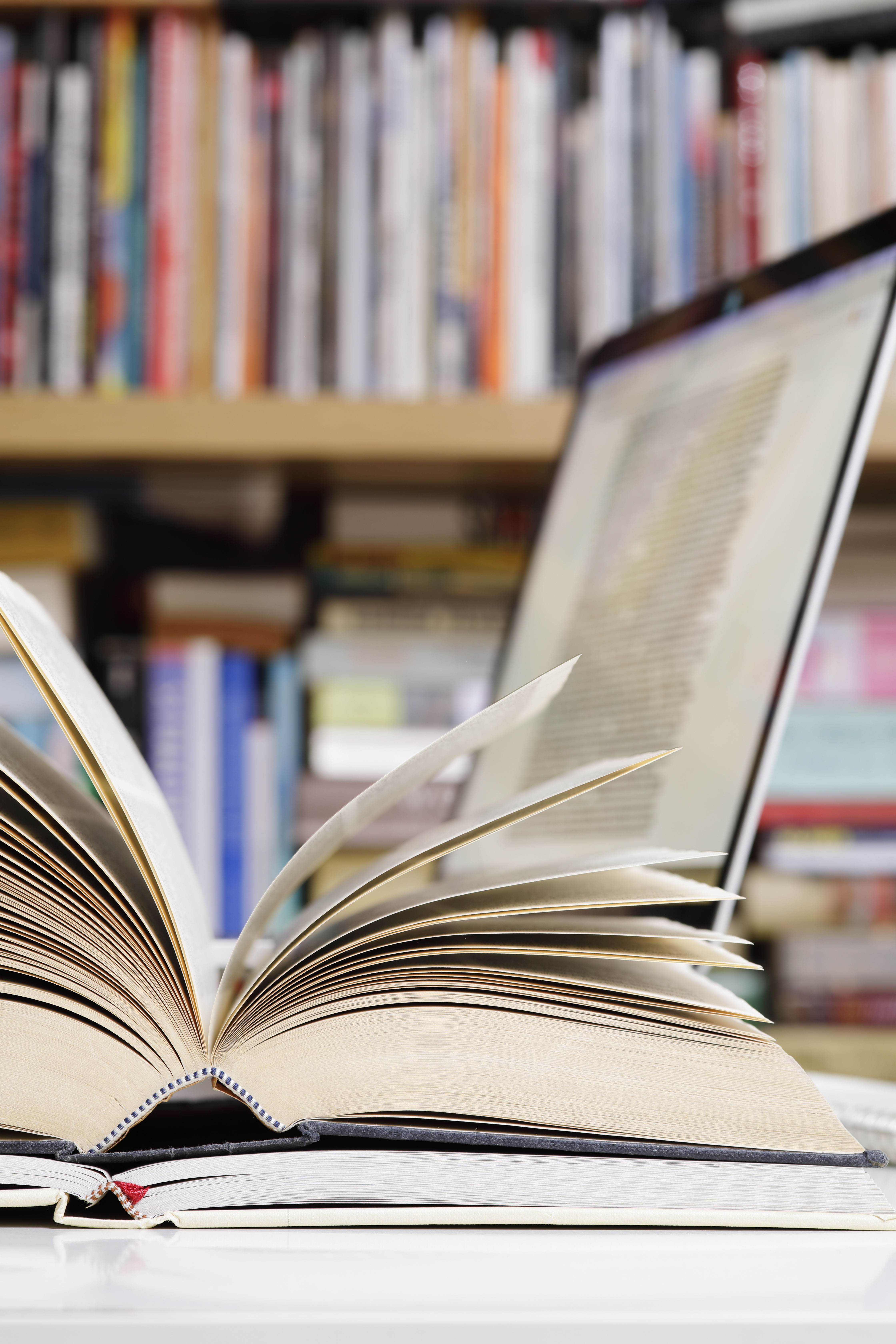 Close up of open books and laptop computer at a library