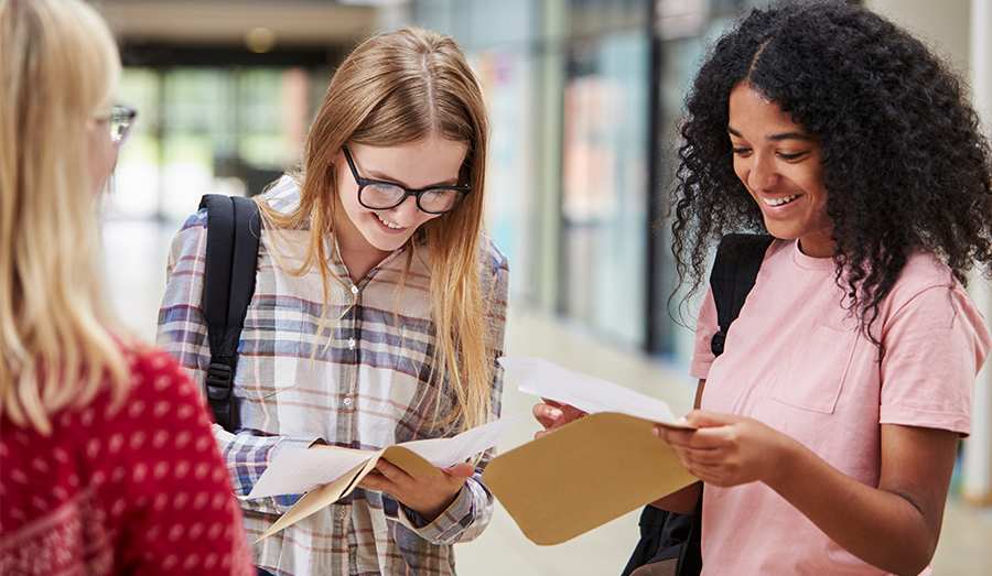 A group of students opening envelopes to discover their exam results.
