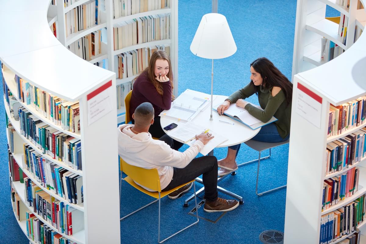 Three students sat in Newport campus library studying together