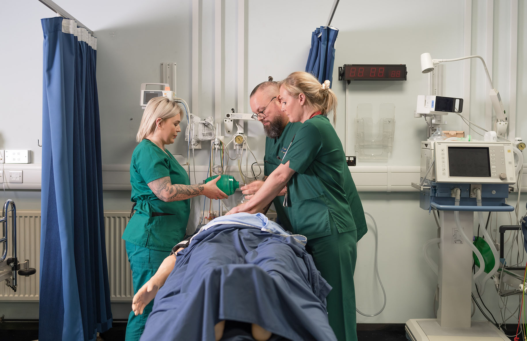 Three health students practicing CPR on a mannequin in the clinical simulation centre