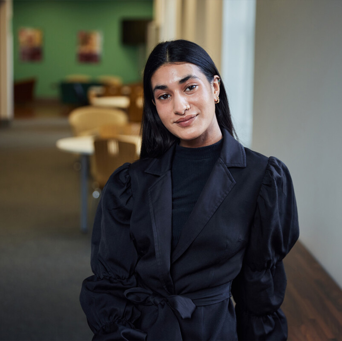Business and Management student, Samaya Khan, is sat in the postgraduate centre, smiling at the camera.