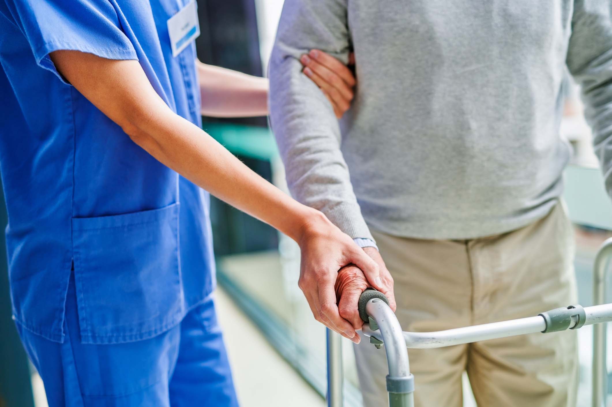 Shot of an unrecognizable female doctor helping a patient with a walker at a clinic