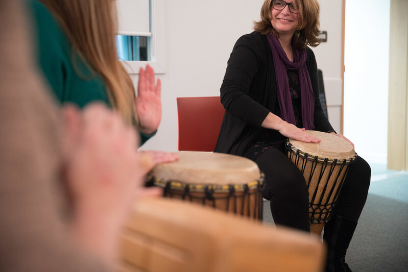 A group of music therapy students sat together playing bongo drums,