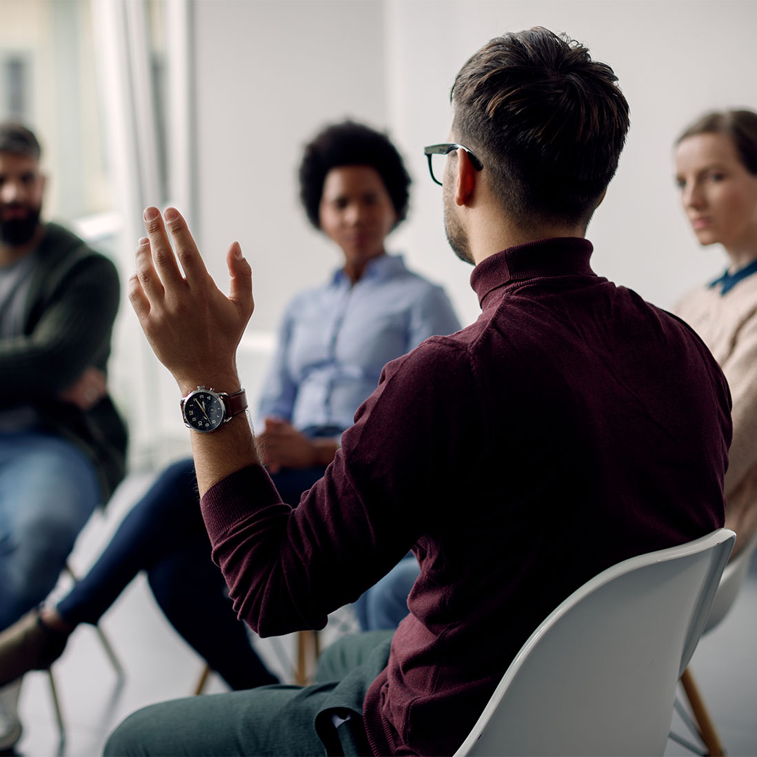 A person raises their hand while sat in a circle with others as part of a group activity