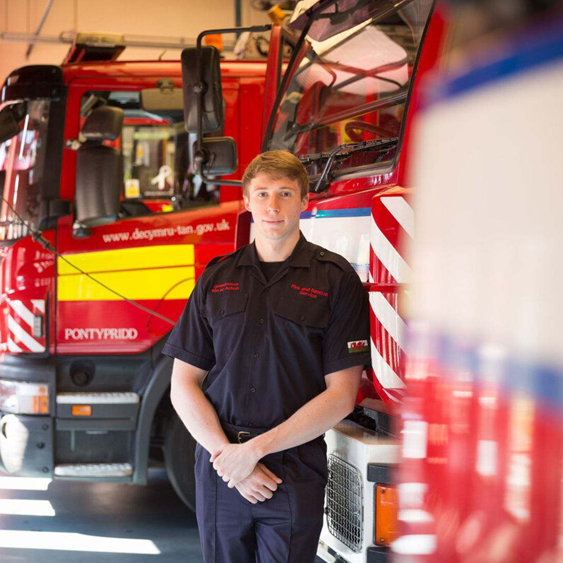 A student in uniform stood in front of 2 fire engines