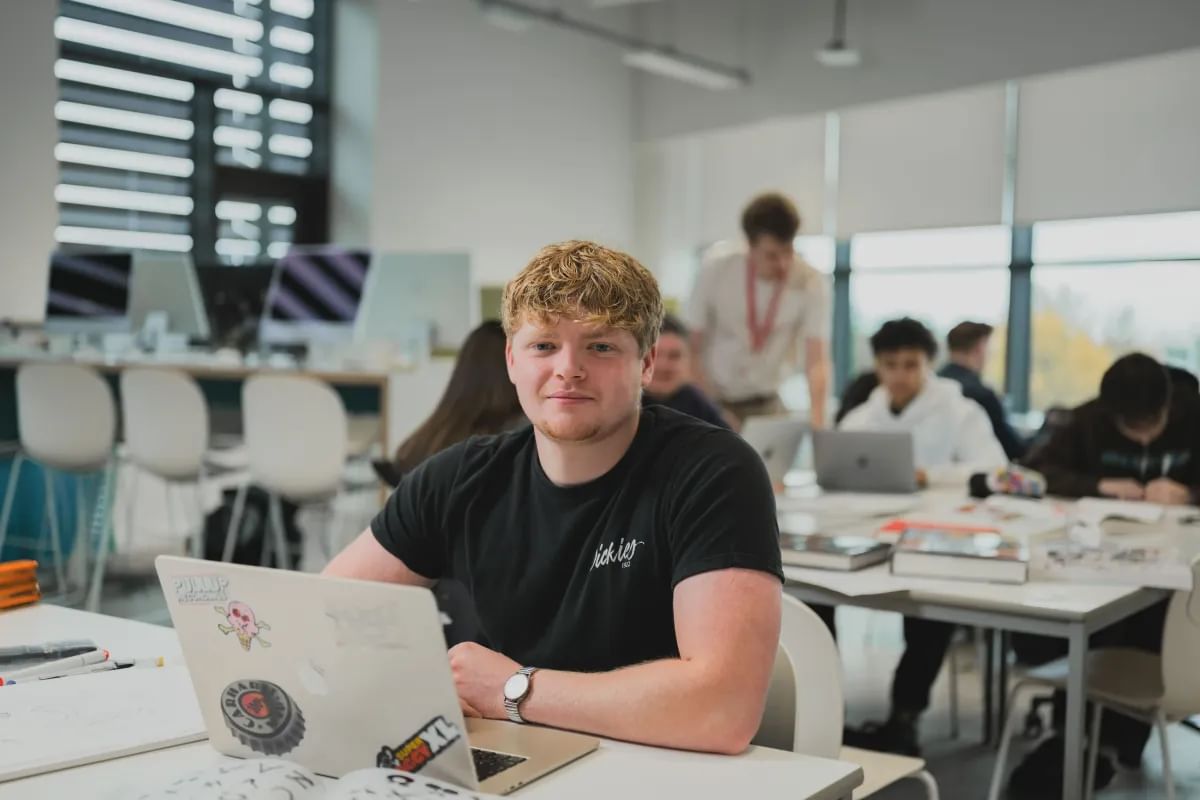 Student sat at a desk working on a laptop