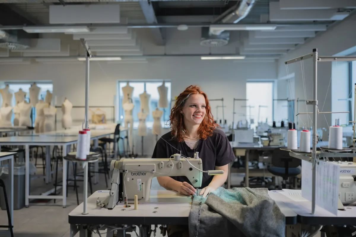 Fashion design student working on a piece of clothing, using a sewing machine in a fashion studio