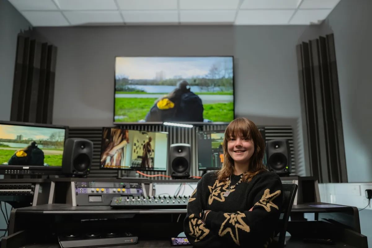 Film student, Lucy, smiles at camera whilst sat in an editing suite