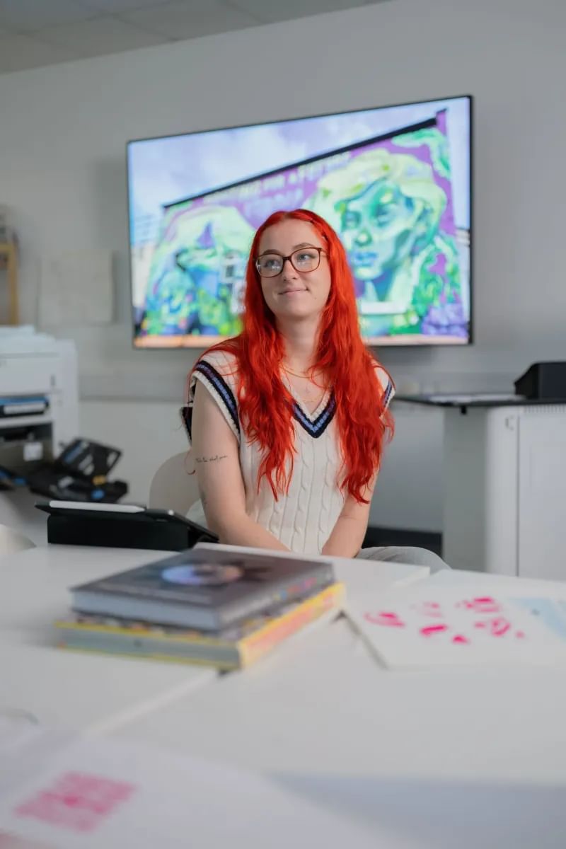 Illustration student smiling, looking away from the camera, whilst working on a project