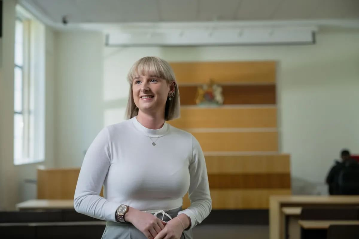 Law student Emily, smiles away from the camera in the Moot courtroom