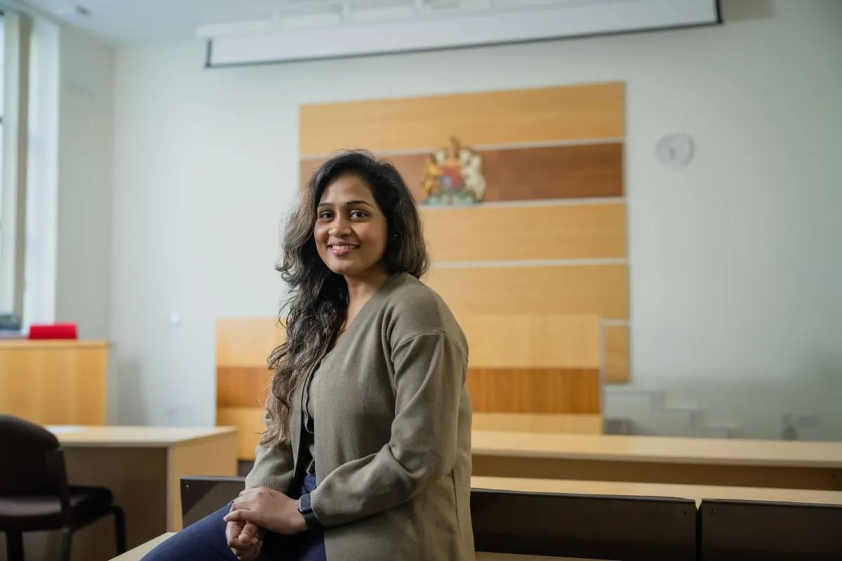 A law student smiles while seated in the moot court