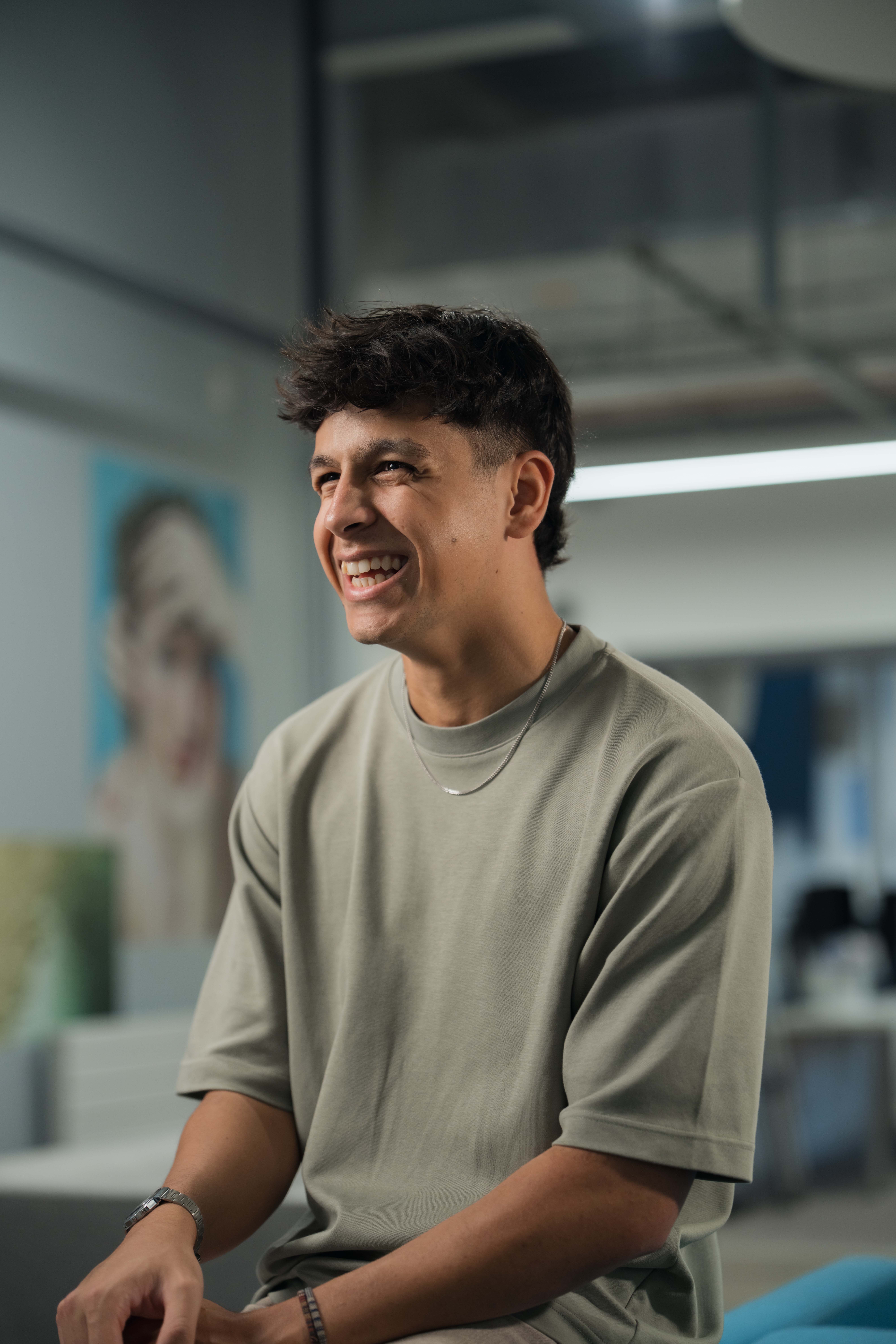 Marketing student, Cole, sits in front of colourful artwork whilst smiling at the camera