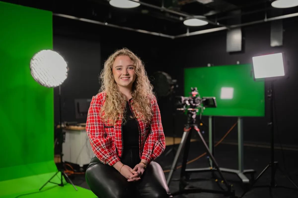 Media Production student, Amelia sits for a profile shot in front of a green screen and camera equipment