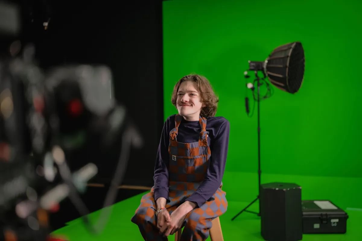 Media Production student, Callum, poses for a photo in front of a green screen