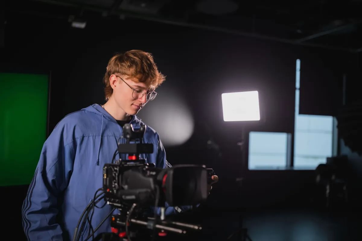 Media Production student, Theo, looking at a camera in a film studio