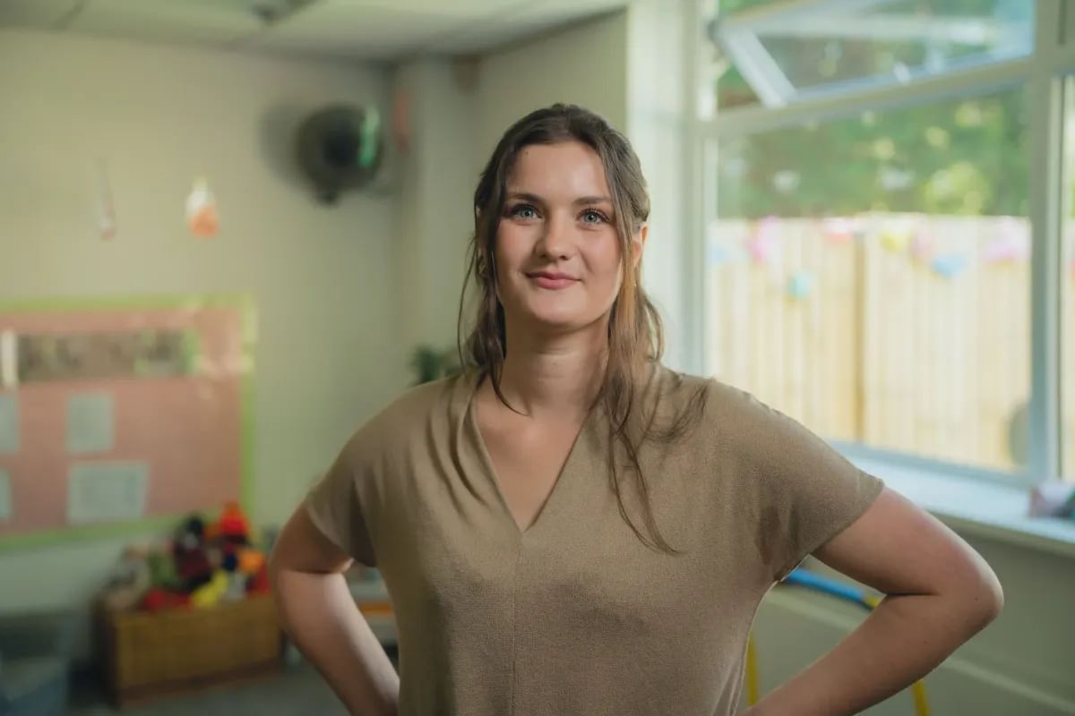 A female psychology students stands confidently in front of the camera whilst smiling
