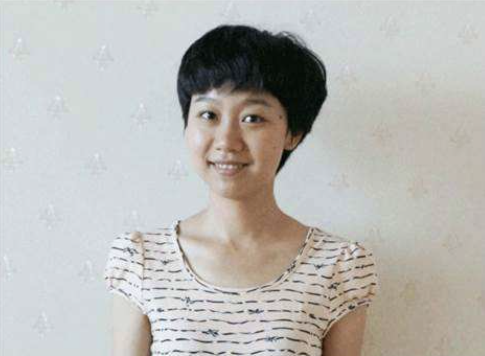 MBA student Zhou Wenxin smiles at the camera in front of a white background