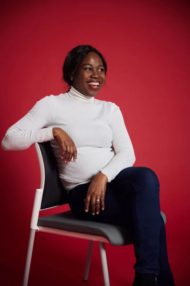 Chidinma sits in front of red backdrop smiling at camera