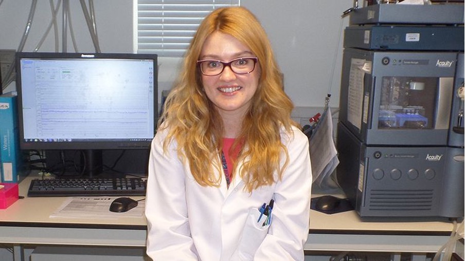 Graduate Emily wearing a lab coat at her workplace