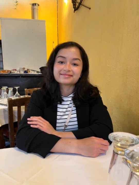 A photograph of Norwegian student, Emma, smiling at the camera in a cafe