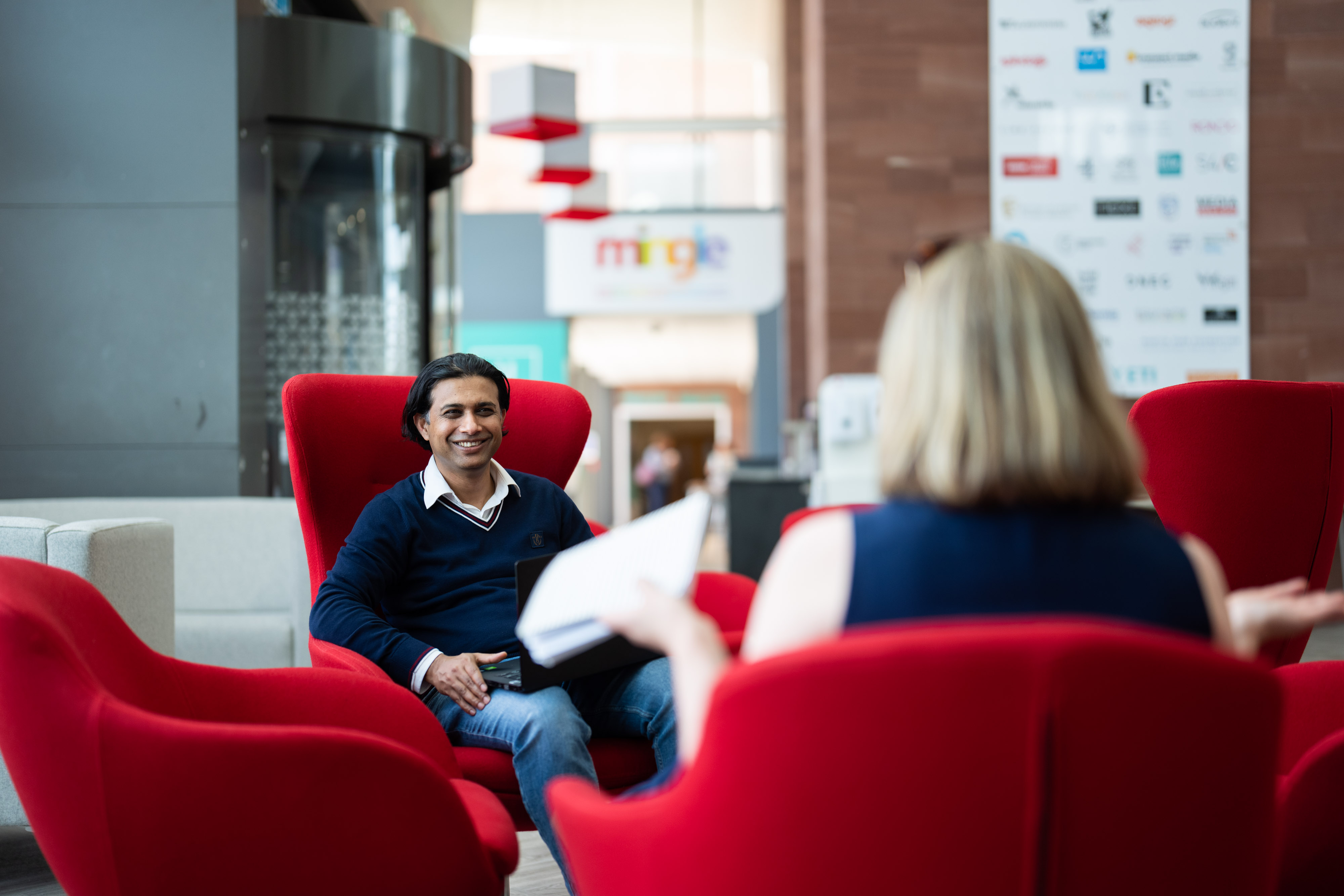 two academics sitting in University foyer talking to each other